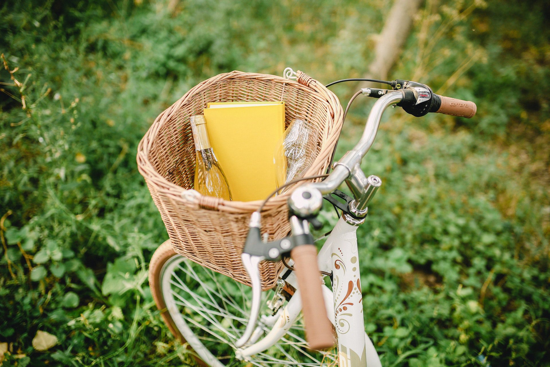 white bicycle with a basket on the front carrying wine and a wine glass for a biking wine tour in Summerland
