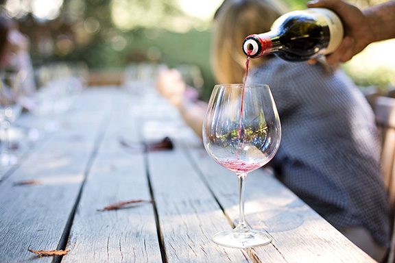 Summerland winery picnic table with an empty wine glass and wine bottle pouring into it